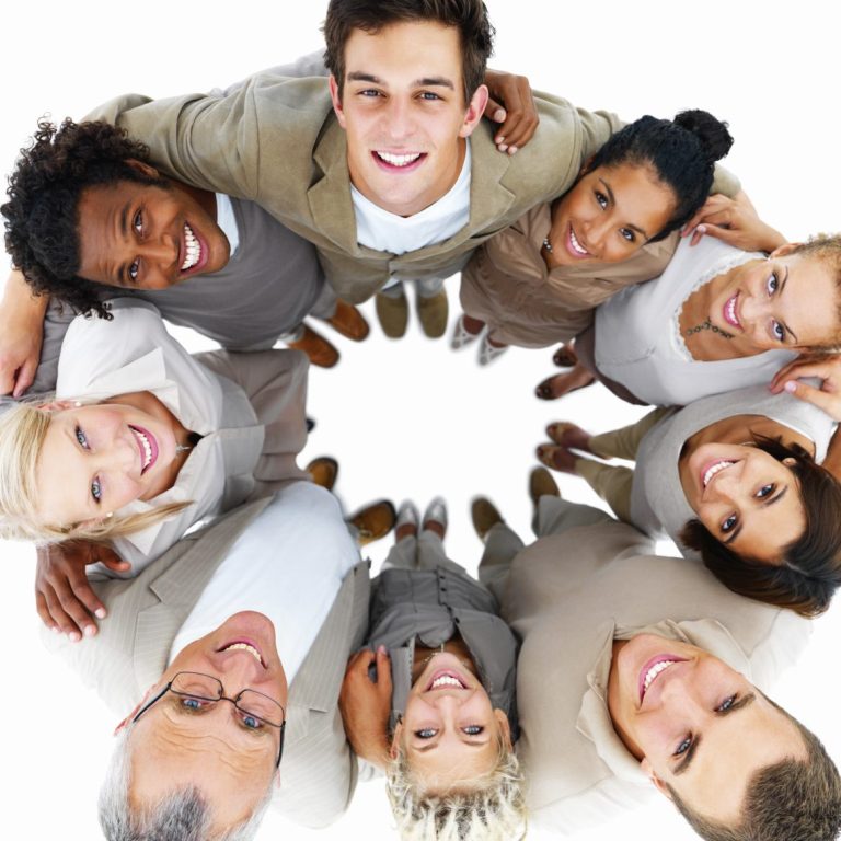 Groupe de personnes diverses souriantes se tenant en cercle, comme une équipe, regardant vers le haut.